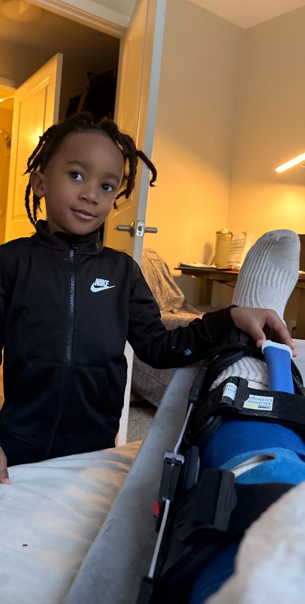 Founder at home during recovery from a full patellar tendon rupture, with his son beside him